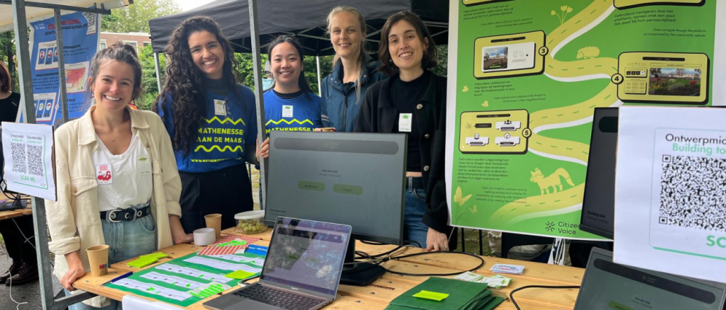 Project team of five ladies standing at a booth with digital tools to be tested by residents.